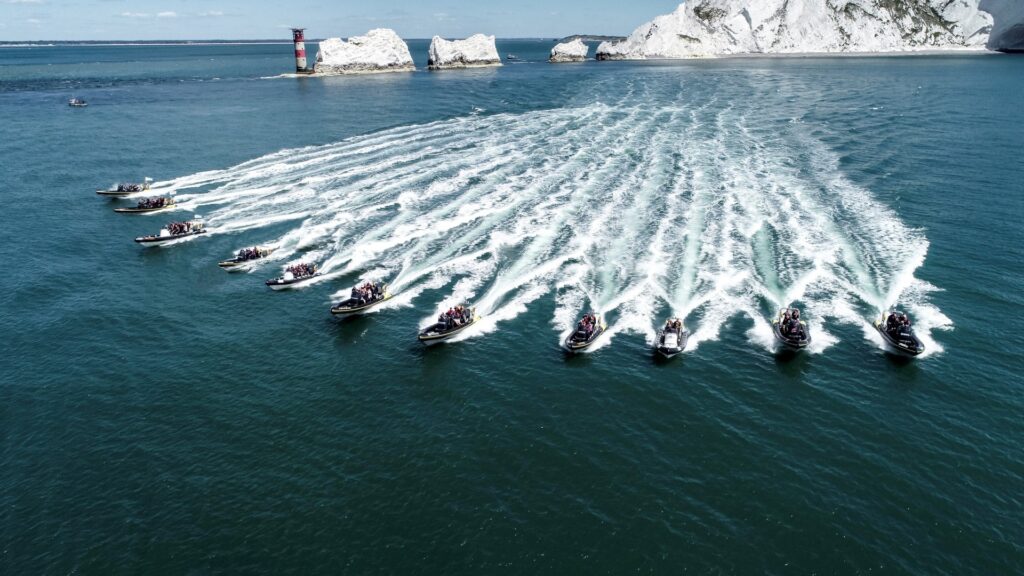 Fleet of RIBs cruising past The Needles on the Isle of Wight during a Solent boating adventure from Lymington
